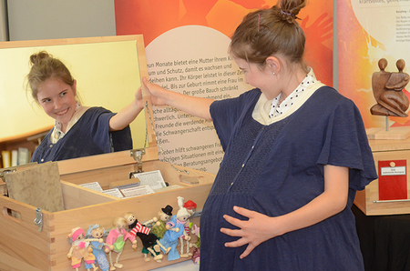 Alina (11 Jahre) mit umgebundenem Babybauch; Ausstellung 'LebenErleben' der aktion leben / Schwangerschaft für Kinder aufbereitet