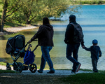 Eine junge Familie beim Spaziergang mit Kindern und Kinderwagen.