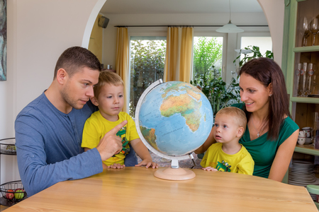 Eine Familie sitzt bei einem Globus und plant eine Reise in den Urlaub