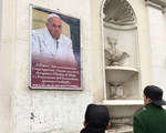 Ein papstkritisches Plakat an einer Wand in Rom am 5. Februar 2017. Zwei Passanten stehen davor und betrachten das Plakat. Unter dem Foto von Papst Franziskus steht in römischem Dialekt: 'Franziskus, du hast Kongregationen unter kommissarische Leitun