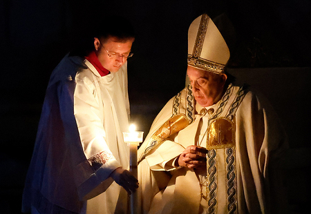 Ein Messhelfer reicht Papst Franziskus zu Beginn der Osternachtsmesse im Petersdom im Vatikan am 30. März 2024 seine Kerze, die an der Osterkerze entzündet wurde.