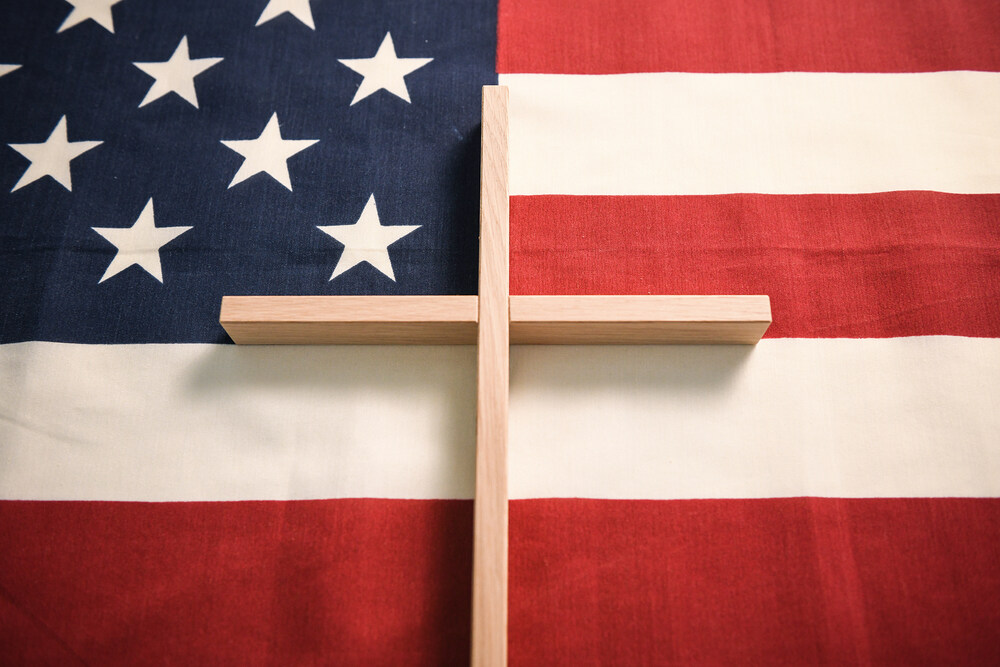 Kreuz und US-Flagge / Copyright 2020, PubliKath GmbH, www.kna.de, All Rights Reserved, Julia Steinbrecht Ein helles Holzkreuz liegt auf einer US-amerikanischen Fahne am 2. Dezember 2020 in Bonn.