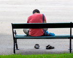 Mann sitzt auf einer Bank, Symbol für Einsamkeit, Depression, Krise