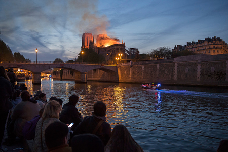 Menschen stehen am Ufer der Seine und blicken auf den Brand der Kathedrale Notre-Dame in Paris am 15. April 2019.