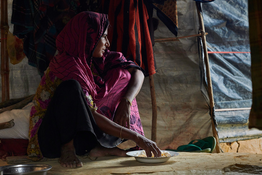 Rohingya in Bangladesch / Copyright 2017, KNA (www.kna.de). Alle Rechte vorbehalten, Paul Jeffrey Eine Angehörige der Rohingya isst Reis mit den Händen von einem Teller und schaut aus ihrer selbstgebauten Unterkunft am 27. Oktober 2017 im Flüchtlingslager Chakmarkul nahe Cox's Bazar (Bangladesch).