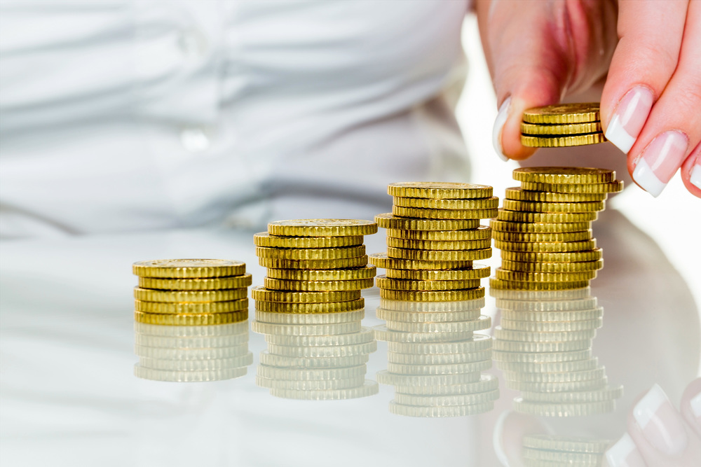Eine Frau stapelt Münzen. Geld sparen für die Zukunft.