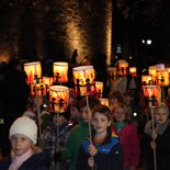 Kinder / Jungen und Mädchen halten rot-gelbe Laternen in den Händen / Hand.  Auf den Laternen sind Kinder, die sich an den Händen halten, dargestellt.  Sankt Martins Umzug  am 10. November 2014 in Rheinbach.