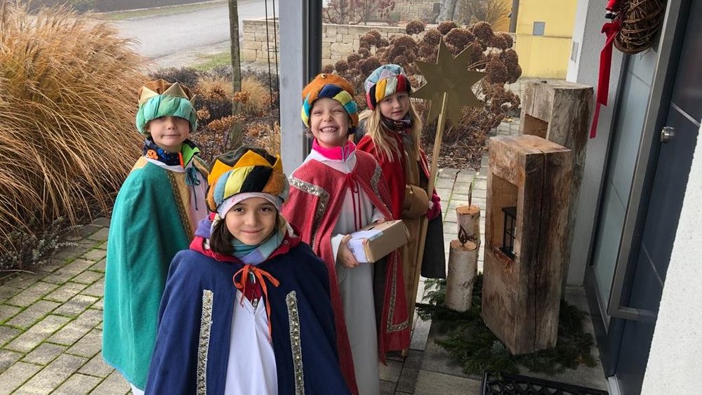 Gruppe von Sternsingerkindern klingelt an Haustüre / Dreikönigsaktion / Thaller