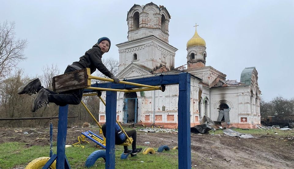 Kind spielt im ukrainischen Kriegsgebiet vor einer Kirche