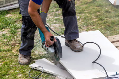 Ein Fliesenleger bei der Arbeit. Zerschneidet Platten mit einer Trennscheibe