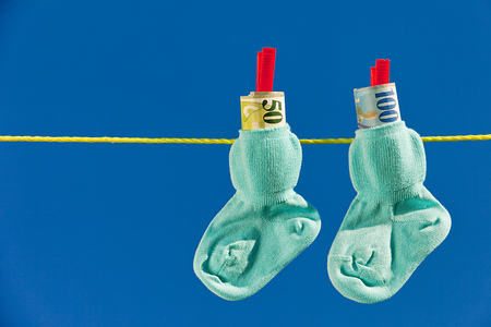 Baby Socken auf W?scheleine mit Schweizer Franken. Blauer Himmel.