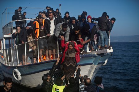 Flüchtlinge und Freiwillige helfen einer Frau von einem Holzboot am Strand von Lesbos am 7. November 2015.