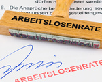 Ein Stempel aus Holz liegt auf einem Dokument. Aufschrift Arbeitslosenrate