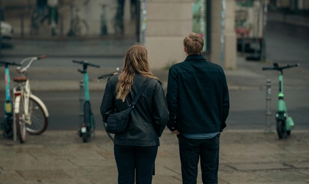Zwei Personen beobachten städtische Spiegelung / Zubair Rafiq Tagung in Wels: 'Mit Unsicherheit Freundschaft schließen'