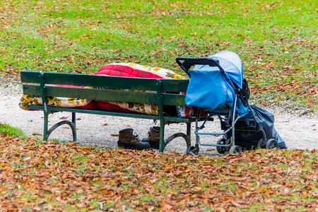Auf einer Parkbank hat sich ein Obdachloser zum schlafen niedergelegt