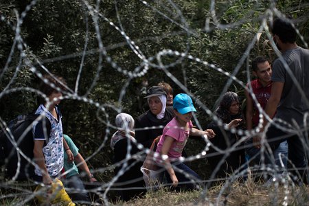 Flüchtlinge in Ungarn / © 2015 KNA, www.kna-bild.de - Nutzungsrechte vorbehalten., Marko Drobnjakovic Flüchtlinge überwinden am 3. September 2015 einen Stacheldrahtzaun an der serbisch-ungarischen Grenze in Röszke. Die Flüchtlinge klettern über den inzwischen 175 Kilometer langen Zaun an der Grenze zwischen Serbien und Ungarn.