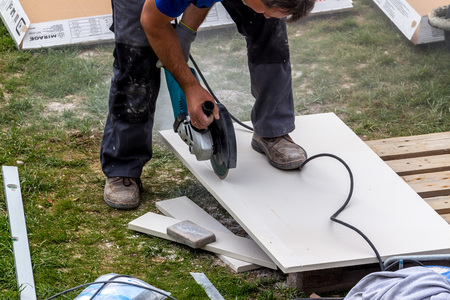 Ein Fliesenleger bei der Arbeit. Zerschneidet Platten mit einer Trennscheibe