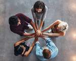 Young people putting their hands on top of each other symbolizing unity and teamwork. Diverse group of students stacking their hands.