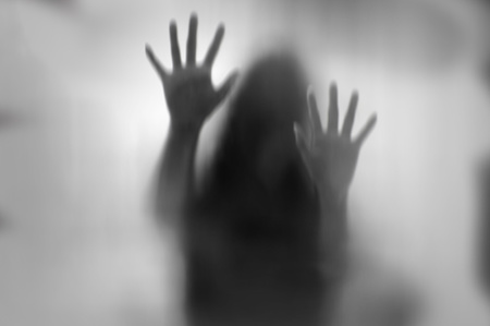 Horror woman behind the matte glass in black and white. Blurry hand and body figure abstraction.