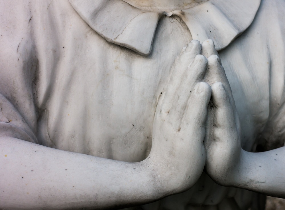 Ein Engel mit betenden Händen auf einem Friedhof. Symbol für Schutzengel oder Friedensengel