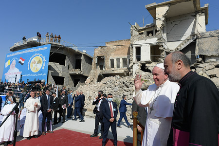 Papst Franziskus gedenkt in einer Zeremonie der Kriegsopfer in Mossul am 7. März 2021. Im Hintergrund stehen zerstörte Gebäude.