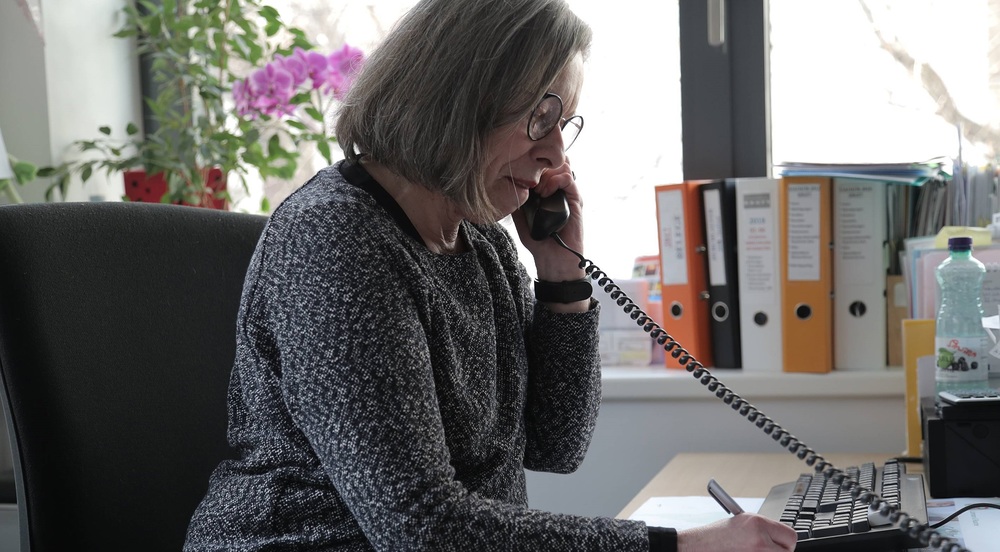 Frau am Telefonhörer / Caritas / Christian Steiner