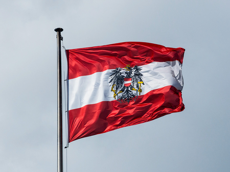 Die österreichische Fahne weht im Wind vor blauem Himmel. Flagge Österreich