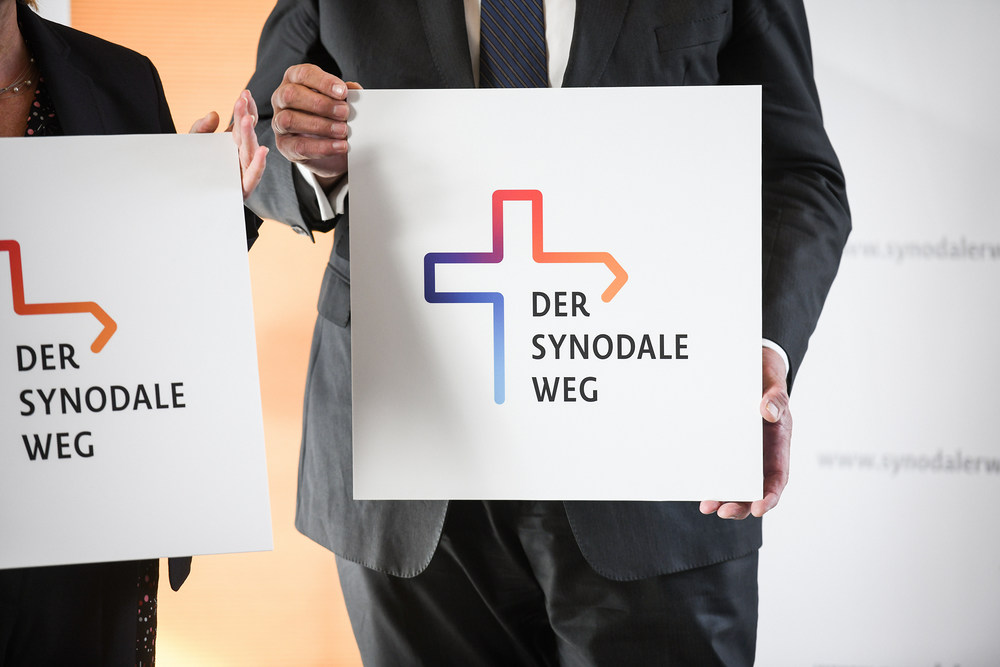 Hände halten ein Schild mit dem Logo zum geplanten Dialog zur Zukunft der katholischen Kirche in Deutschland am 8. November 2019 in Bonn.