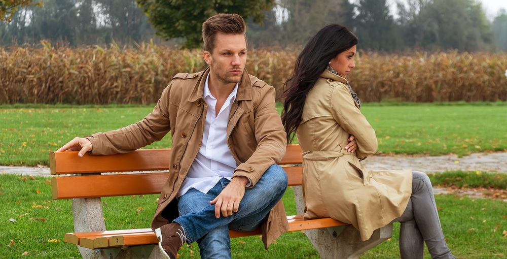 Ein junges Paar sitzt auf einer Parkbank und streitet