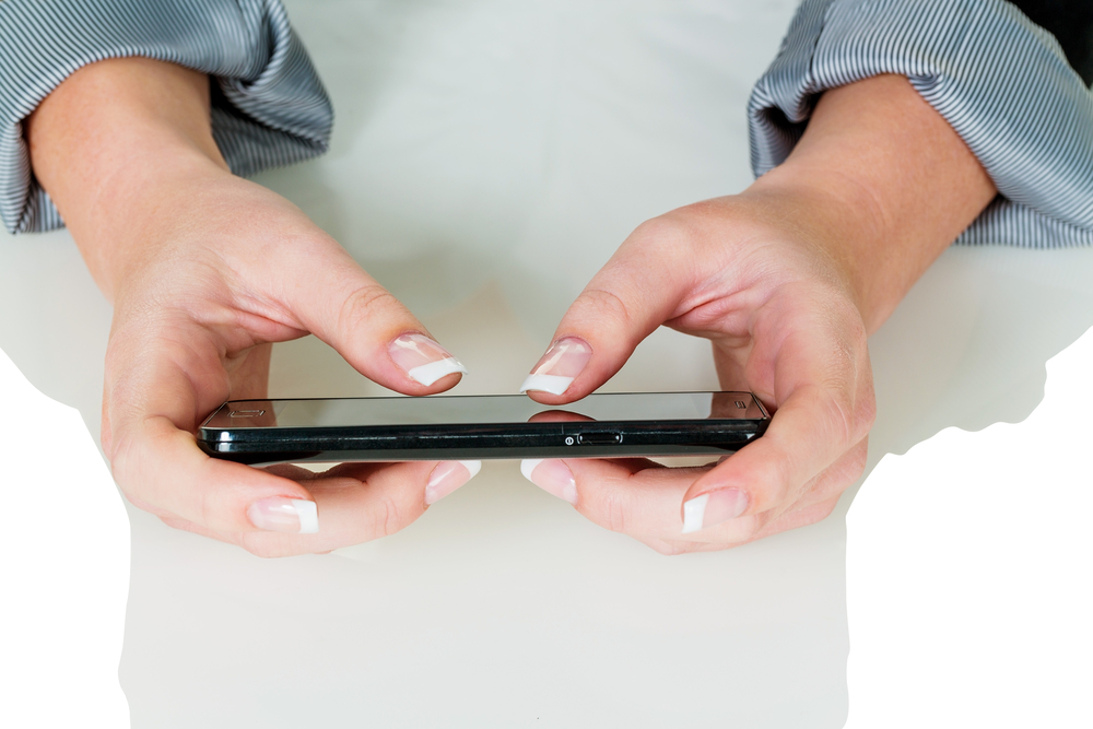 Eine Frau schreibt auf einem Handy eine SMS. Schnelle Kommunikation durch Mobiltelefon.