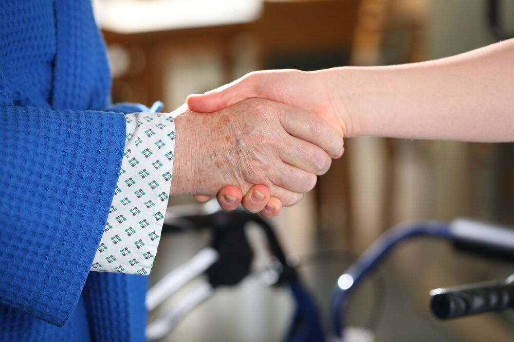 Patientin und Ärztin oder Pflegerin reichen sich die Hand / Barmherzige Brüder Patientin und Ärztin oder Pflegerin reichen sich die Hand