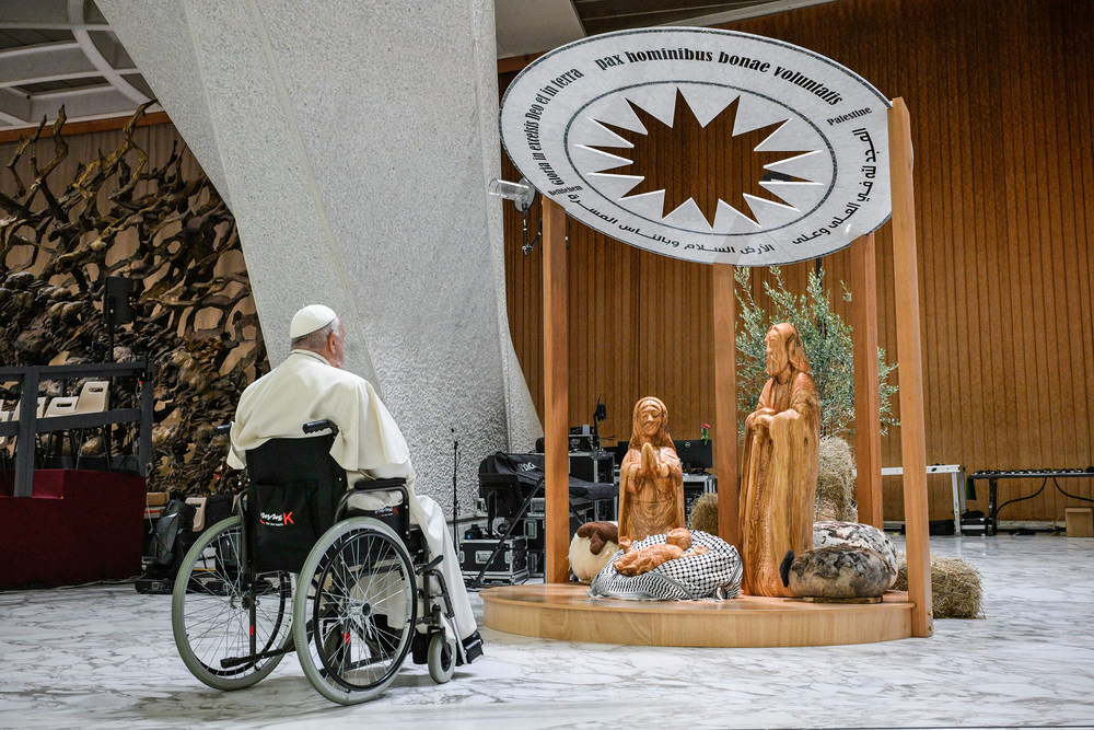 Papst Franziskus betet vor der Krippe am 7. Dezember 2024 in der Audienzhalle im Vatikan. Das Jesuskind liegt auf einem schwarz-weißen Palästinensertuch.