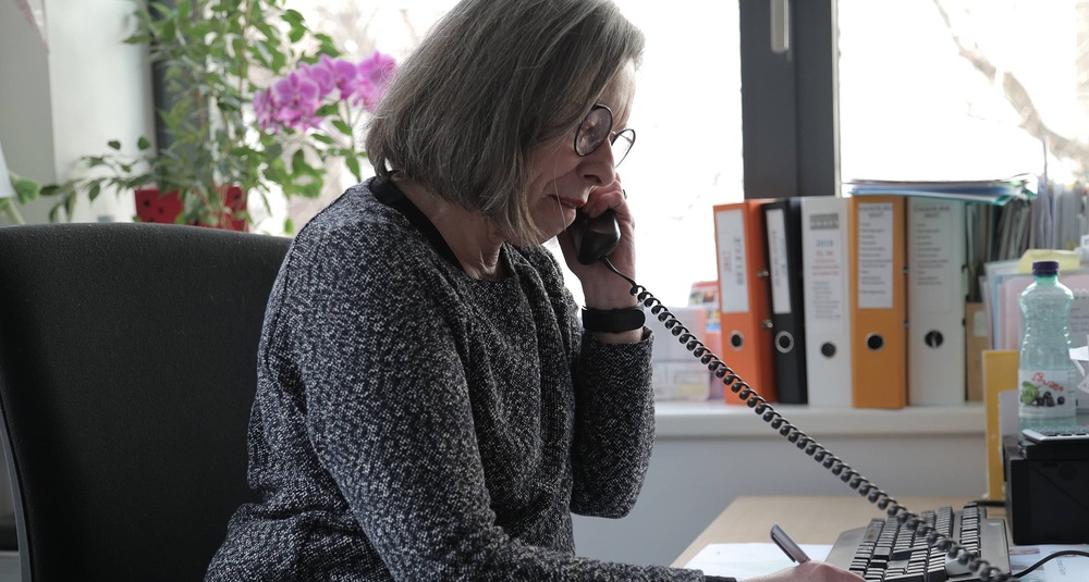 Frau am Telefonhörer / Caritas / Christian Steiner