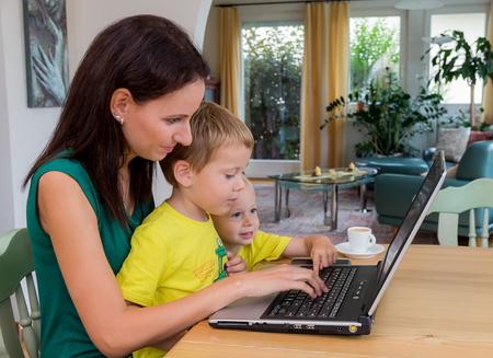 Eine junge Frau arbeitet zu Hause im Heimb?ro und hat ein Kind an ihrer Seite