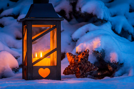 Eine Laterne leuchtet im Schnee zu Weihnachten. Romantisches Licht an einem Abend im Winter. Stille und Ruhe