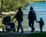 Eine junge Familie beim Spaziergang mit Kindern und Kinderwagen.