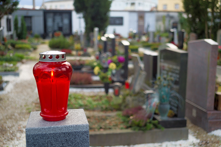 Eine rote Laterne leuchtet vor Gr?bern auf einem Friedhof