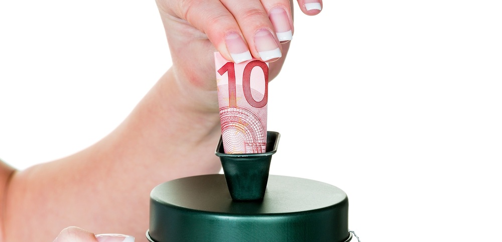 Eine Hand hält eine Spendensose. Es wird Geld gesammelt.