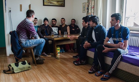 Flüchtlinge sitzen um Tisch