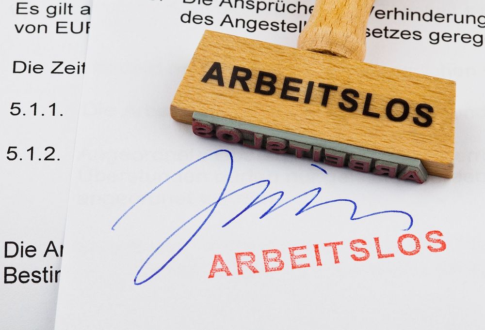 Holzstempel auf Dokument: arbeitslos / Erwin Wodicka Ein Stempel aus Holz liegt auf einem Dokument. Deutsche Aufschrift: arbeitslos