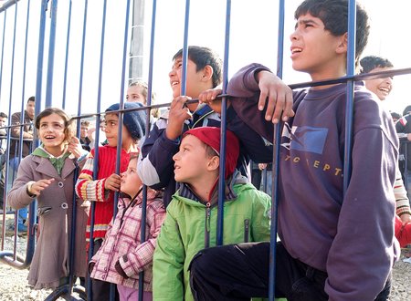 Flüchtlingskinder blicken durch einen Zaun im kroatischen Transit-Camp Slavonski Brod. Freiwillige Helfer haben sich als Clowns verkleidet und versuchen, die Kinder zum Lachen zu bringen.