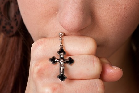  Junge Frau betet mit einem Kreuz in der Hand