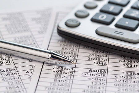 Ein Taschenrechner liegt auf den Zahlen einer Bilanz uns Statistik. Symbolphoto f?r Umsatz, Gewinn und Kosten.