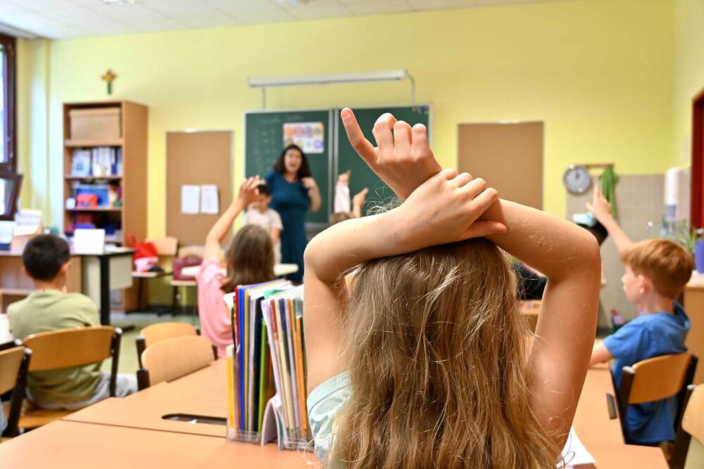 Kinder in einer Klasse zeigen auf