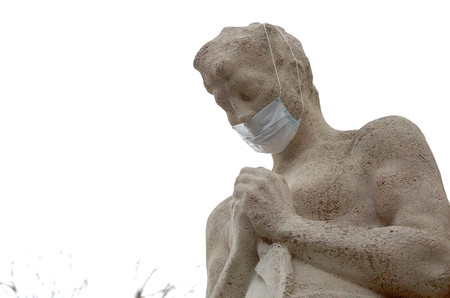 Mit Mundschutz verhüllte Statue 'Betender Bauer' vor der Kirche St. Josef in Wien-Essling