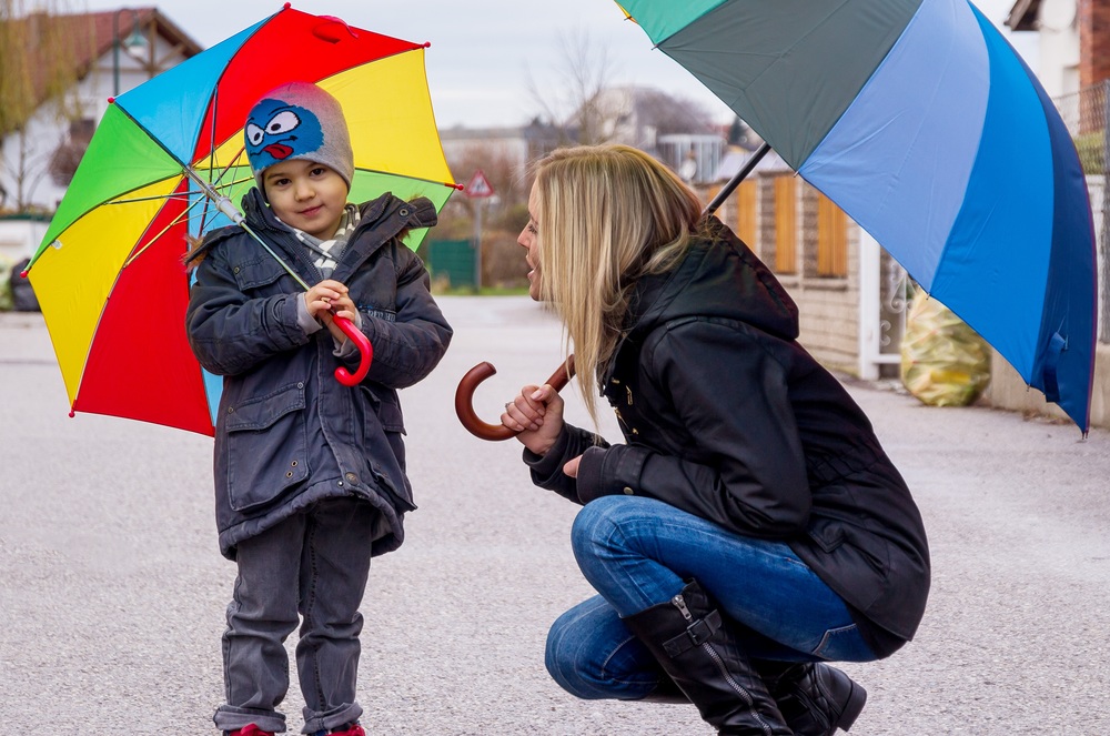 Mutter und Kind mit Regenschirm, Symbol für Solidarität, Hilfe, Hilfspaket, Rettungsschirm, 