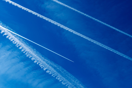 Die Kondensstreifen von mehreren Flugzeugen vor blauem Himmel