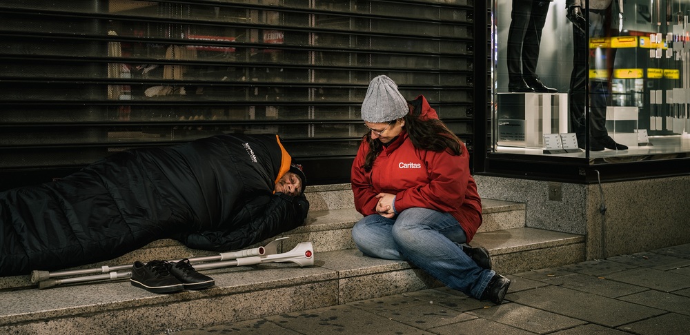 Caritas-Streetworkerin mit Obdachlosem im Winter