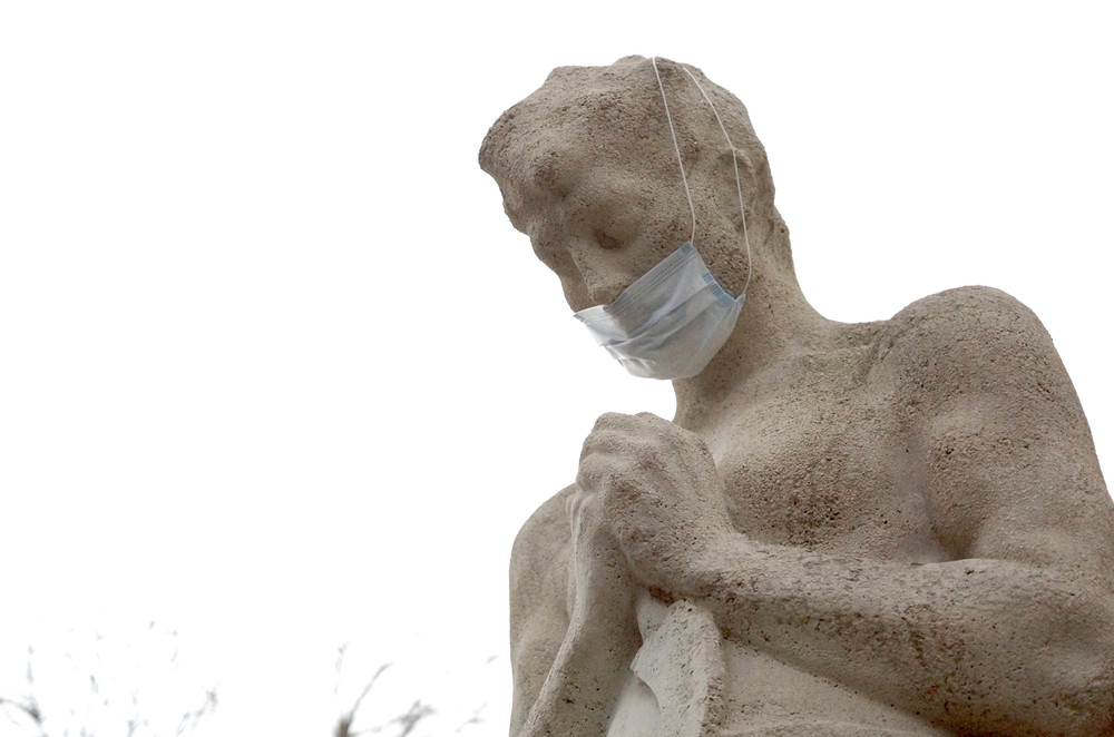 Mit Mundschutz verhüllte Statue 'Betender Bauer' vor der Kirche St. Josef in Wien-Essling