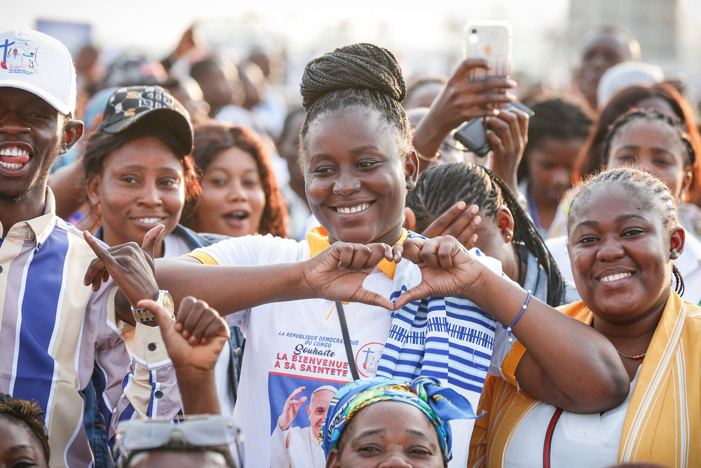 Eine Frau steht in der Menschenmenge und formt mit den Händen ein Herz in Erwartung von Papst Franziskus am 1. Februar 2023 auf dem Flughafen Ndolo in Kinshasa (Demokratische Republik Kongo).